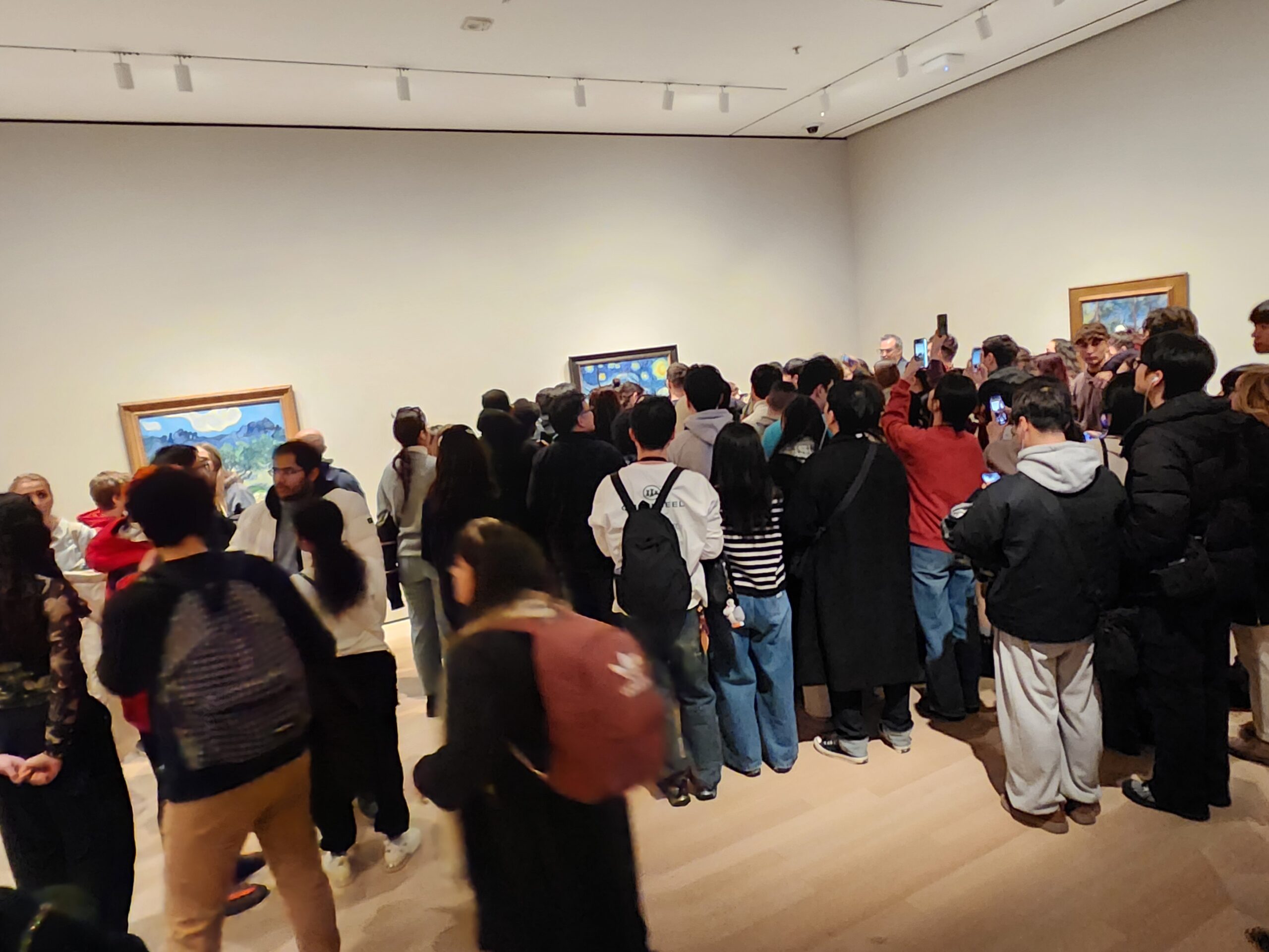 drawing the crowd into a tight knot of bodies and raised phones—it is Vincent van Gogh’s The Starry Night.